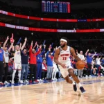 Detroit Pistons player driving with ball as home crowd cheers at Little Caesars Arena